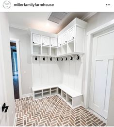 a mud room with white cabinets and benches