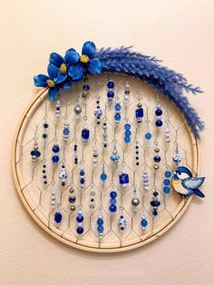 a blue bird is sitting on top of a beaded dream catcher with beads and flowers