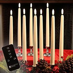 a bunch of candles sitting on top of a table next to pine cones and christmas decorations