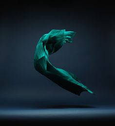 a green object is flying in the air on a dark background with no one around it