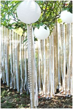 some white paper lanterns hanging from a tree