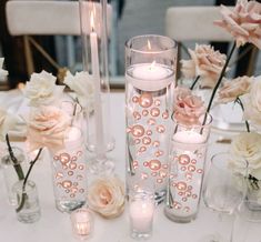 a table with candles and vases filled with pink flowers on top of it,