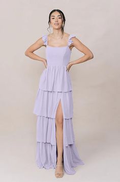 a woman in a lavender colored dress poses for the camera with her hands on her hips