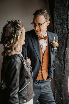 a man in a suit and tie standing next to a woman wearing a flower crown