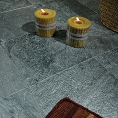 two candles sitting on the floor next to a rug