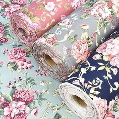 three rolls of fabric with floral designs on the top one is blue, pink and white