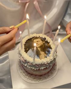 two people lighting candles on a birthday cake with a photo and candle stick in it