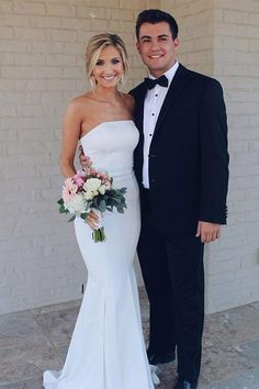 a man in a tuxedo standing next to a woman in a white dress