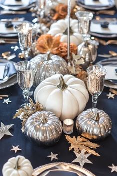 the table is set with silver and white pumpkins, gold stars, and candles