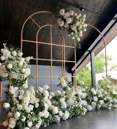 white flowers and greenery are arranged on the wall