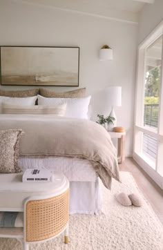 a bedroom with a large bed, white rugs and two tables in front of it