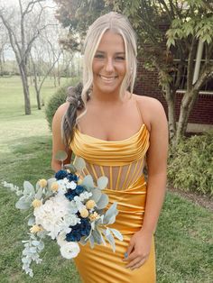 a woman in a yellow dress is holding a bouquet and smiling at the camera while standing outside