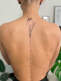 the back of a woman's neck with a flower tattoo on it