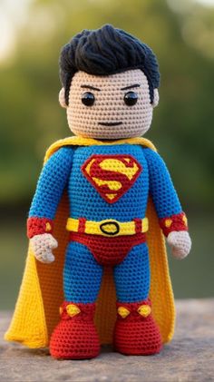 a crocheted superman doll sitting on top of a wooden table with trees in the background