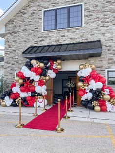 an entrance to a house decorated with balloons and red carpet for the holiday season in front of it