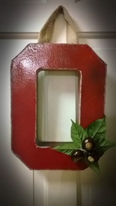 a close up of a red wooden frame with green leaves and bells on the front