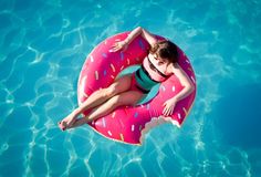 a woman floating on an inflatable donut floatie over the pool water