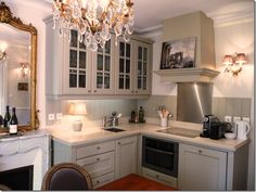 a kitchen with a chandelier hanging from the ceiling and white cabinets in it