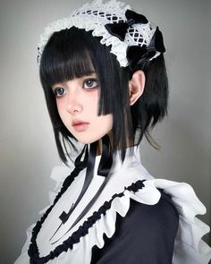 a woman with black hair wearing a white and black outfit