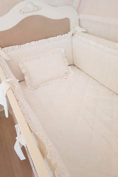 a white crib with some pillows on it