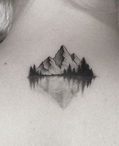 a woman's chest with a mountain and trees tattoo on her upper back side