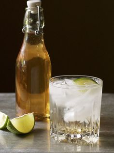 a bottle of soda and a glass filled with ice, limes and lemon wedges