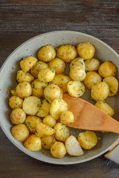 a wooden spoon in a bowl filled with potatoes