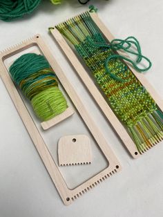 two pieces of wood with green and yellow yarn on them next to a pair of knitting needles