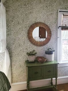 a green table with a mirror and potted plants on it in front of a window