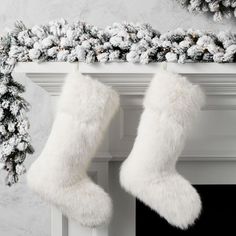 two white christmas stockings hanging from a mantel