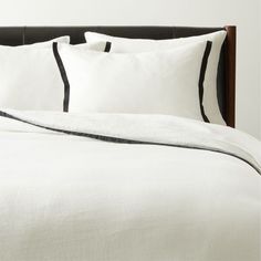 a bed with white sheets and black trims