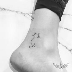 a black and white photo of a small cat tattoo on the left side of the foot