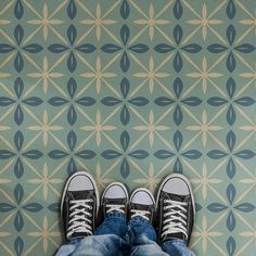 a person with their feet on the ground in front of a geometric wallpaper pattern