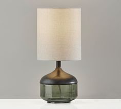 a green glass table lamp with a white linen shade on the top and bottom part