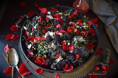 a bowl filled with berries and flowers on top of a metal tray next to a spoon