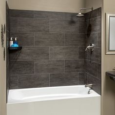 a white bath tub sitting under a bathroom mirror