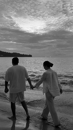 two people walking on the beach holding hands