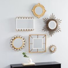 a black dresser topped with lots of mirrors next to a wall mounted sunburst