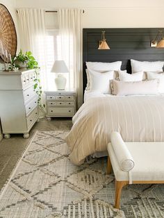 This is an image of a white bed with white pillows and a tan lumbar. There is a tan with white pinstripes duvet at the foot of the bed. The headboard is a black shiplap with gold sconces hanging. Shiplap Headboard, Farmhouse Area Rugs, Bedroom Renovation, Bedroom Area Rug, Décor Diy, Farmhouse Bedroom, Master Bedrooms Decor, Farmhouse Living, Bed Room