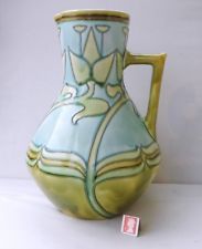 a blue and green vase with designs on it's sides sitting on a white surface