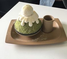 there is a green cake on the plate with whipped cream and coffee cup next to it