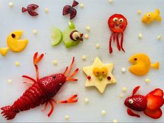 various sea animals made out of food on a white tablecloth with fish, crab, and starfish