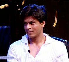 a man in white shirt sitting down with his hand on his hip and looking at the camera