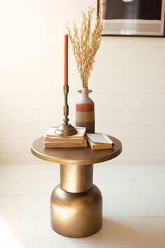 a table that has some books on top of it with a candle in the middle