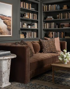 a living room filled with lots of bookshelves next to a couch and table