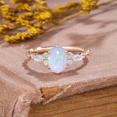 an opal stone ring sitting on top of a wooden table next to yellow flowers