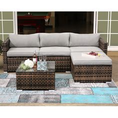 a couch and coffee table sitting on top of a blue rug in front of a house