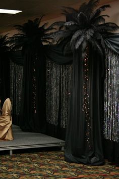 a stage set up with black drapes and palm trees