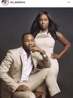 a man and woman sitting on top of a wooden chair next to each other in front of a gray background