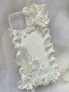 a white cell phone case with flowers and pearls